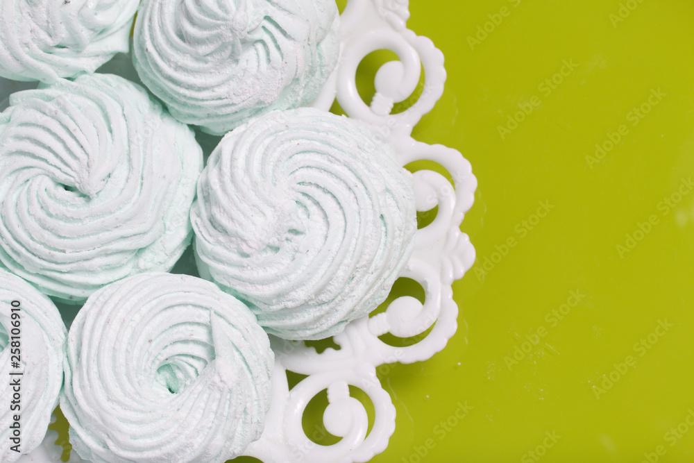 Homemade marshmallows laid on a plate. Marshmallow with mint, with a green tint. On the light green background.