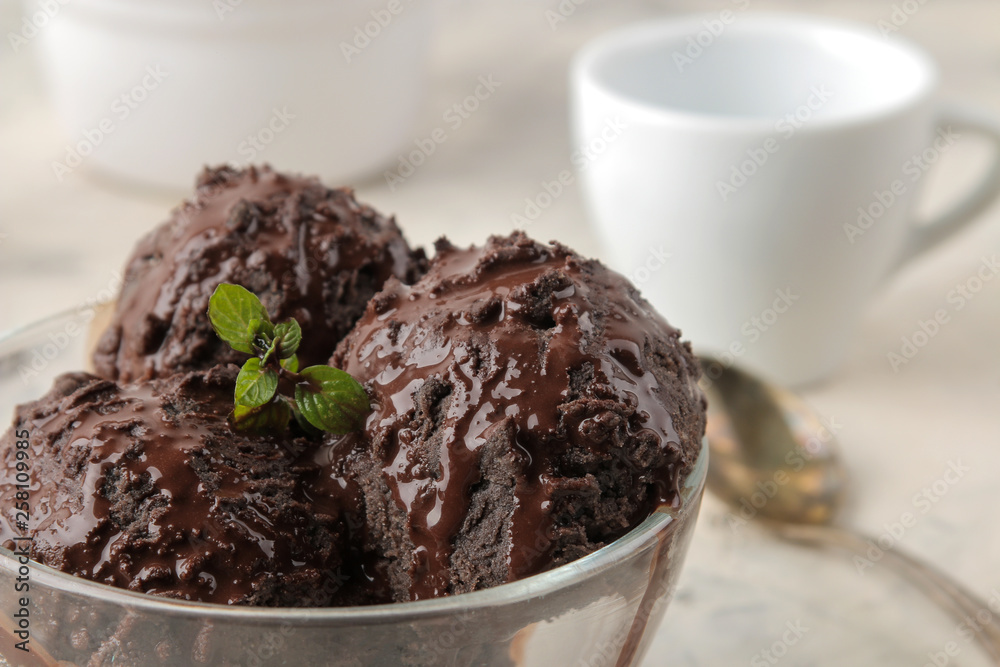 Chocolate ice cream with liquid chocolate on a light concrete background.