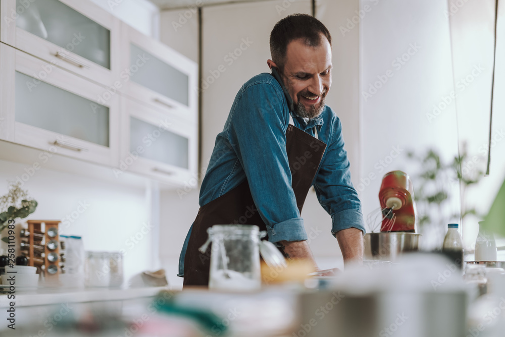 Smiling man talking on the phone while cooking Smiling man talking on the phone while cooking