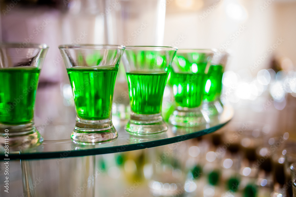 Alcoholic drinks of green color in glass cups