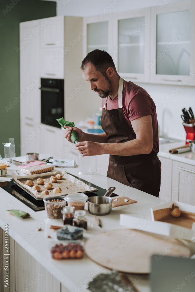 Serious bearded man frowning while using icing bag Serious bearded man frowning while using icing bag