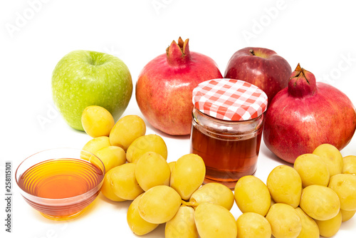 Rosh Hashanah  Jewish New Year  Traditional Symbols  Honey in a glass jar  Pomegranates  Dates  Red And Green Apples. Isolated On A White Background
