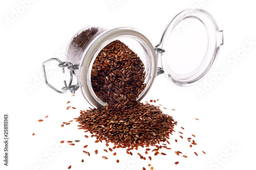 Brown flax seeds in glass airtight jar isolated on white background