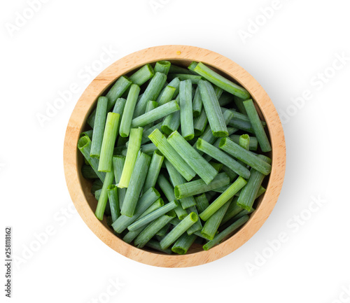 slice green onions in wood bowl on white background. top view
