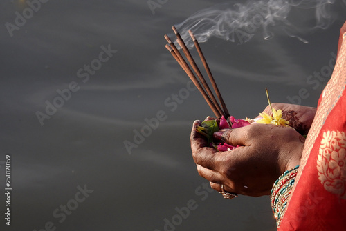  Hindu woman pray sun God, with food offerings, at dusk,in the bank of lake, during annual ritual Chhath Puja