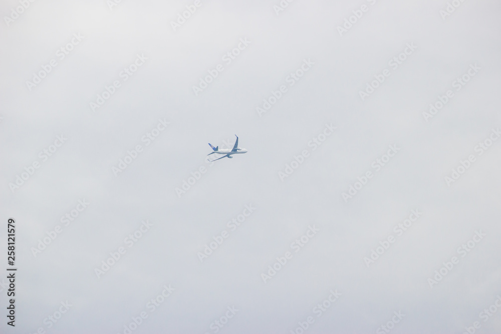 Distant airplane flying in the cloudy sky Distant airplane flying in the cloudy sky