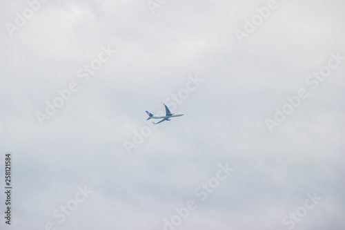 Distant airplane flying in the cloudy sky