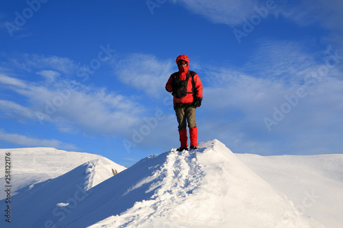 The tourist stands on the ridge of the mountains in the winter mountains