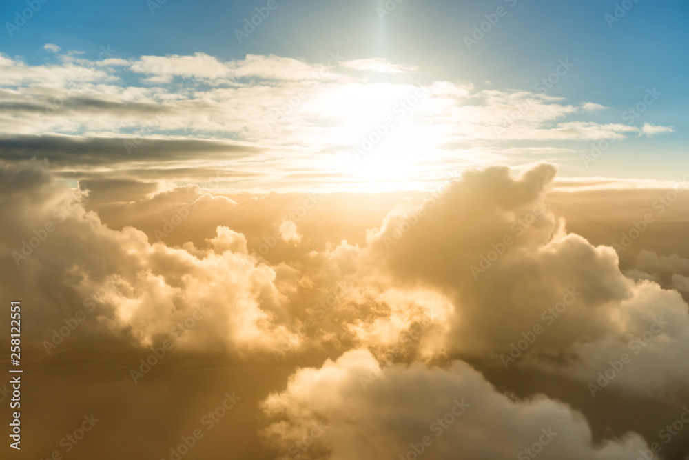 Airplane view of beautiful landscape with gold colored sky clouds, ocean and bright shining sun