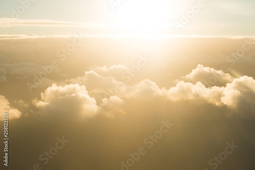 Airplane view of beautiful landscape with gold colored sky clouds, ocean and bright shining sun