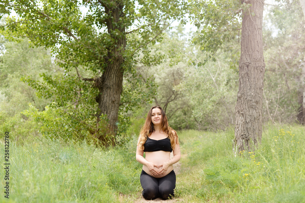 Pregnant beautiful woman yoga outdoors on the grass in sunny summer day Pregnant beautiful woman yoga outdoors on the grass in sunny summer day
