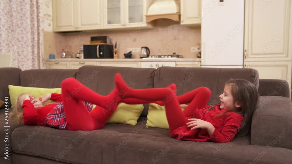 Little cute girls playing on the couch at home.