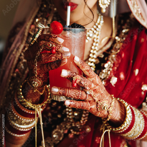 A beautiful bride Hindu girl drinks a cocktail on her wedding day