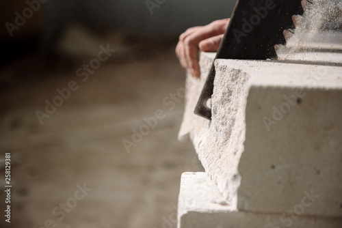 young man sawing a foam block with a saw