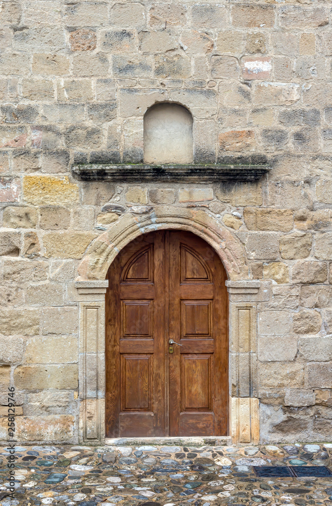 The background old beige stony wall with door The background old beige stony wall with door
