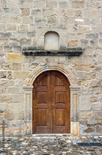 The background old beige stony wall with door