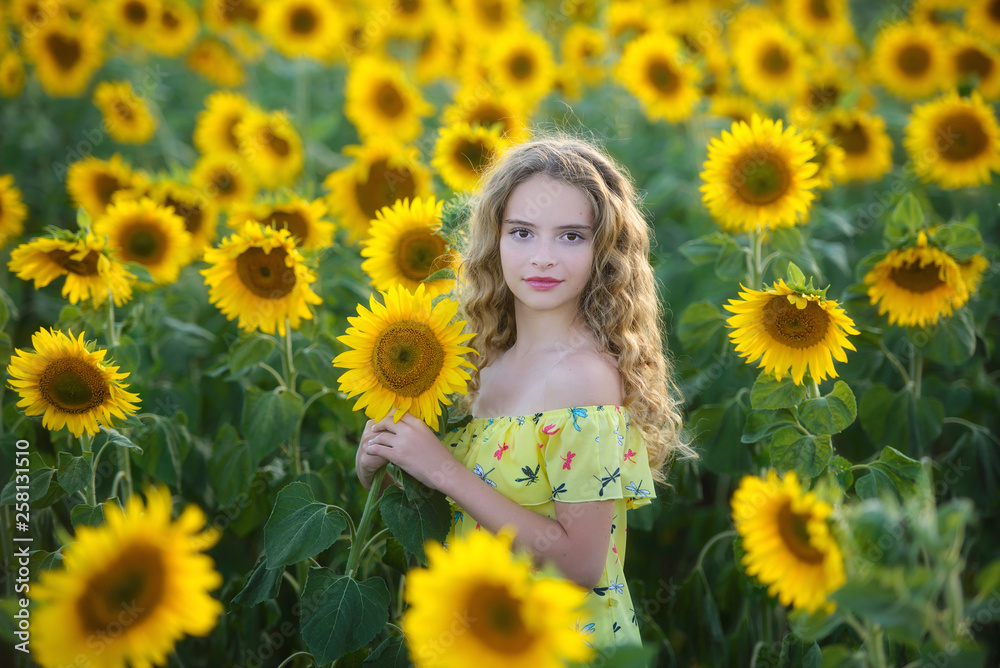 Beautiful young girl enjoying nature on the field of sunflowers at sunset Beautiful young girl enjoying nature on the field of sunflowers at sunset