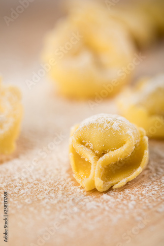Frische, rohe Cappelletti Tortellini Pasta mit Mehl und Grieß auf Holz Brett