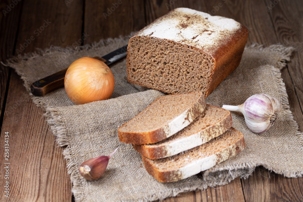 Form rye-wheat bread, sliced pieces, onions and garlic on a natural napkin. Form rye-wheat bread, sliced pieces, onions and garlic on a natural napkin.