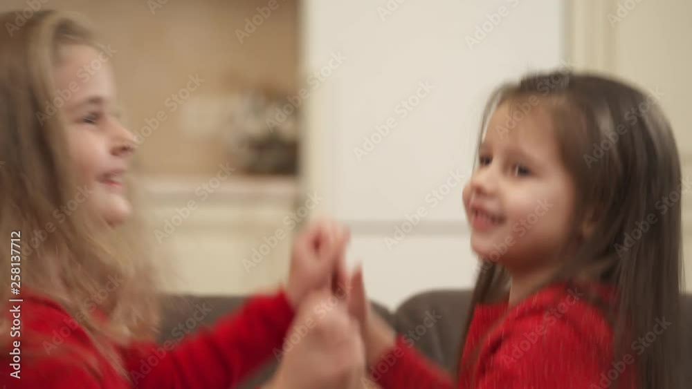 Close-up view of a cute kids holding each other's hands, jumping and falling on a sofa Close-up view of a cute kids holding each other's hands, jumping and falling on a sofa