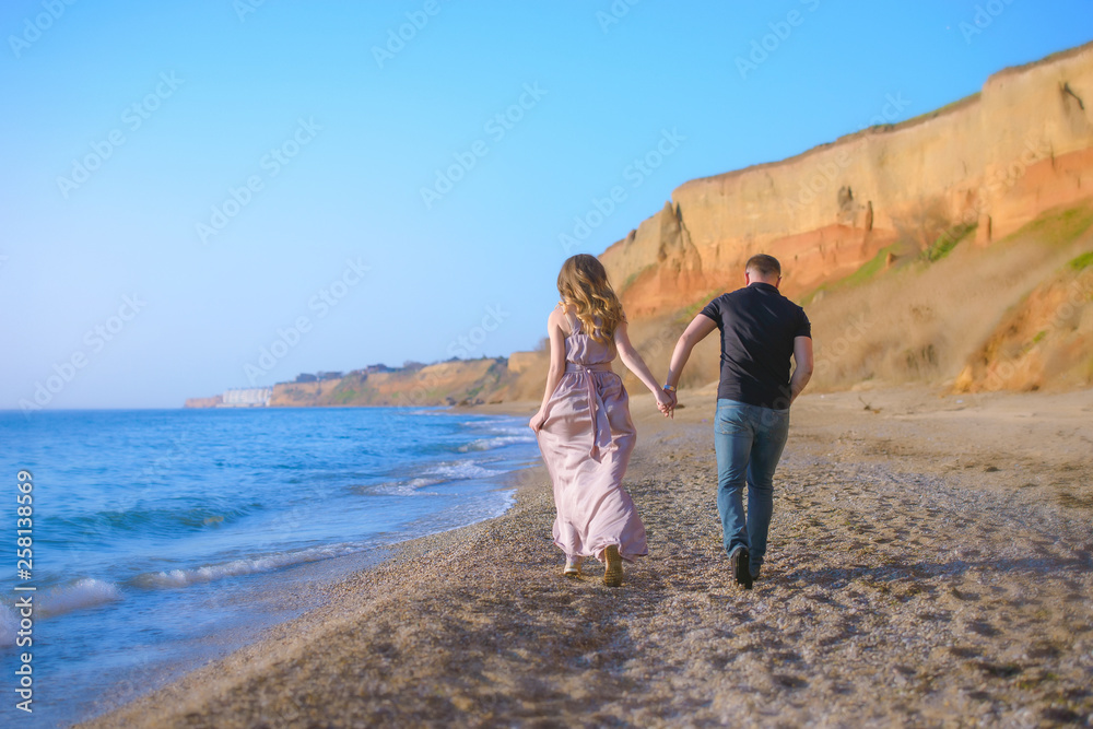 Happy couple runs in wave splashes at romantic sea sunset Happy couple runs in wave splashes at romantic sea sunset