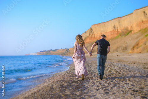 Happy couple runs in wave splashes at romantic sea sunset