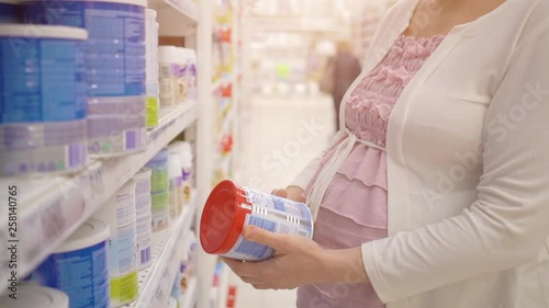 Pregnant woman choosing milk powder in supermarket
