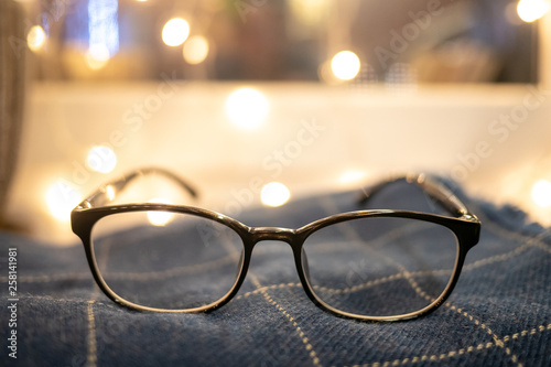 beautiful transparent glasses. beautiful frame for glasses. Eyeglasses on a blue checkered rug. glasses on a blue checkered table. Glasses on a white background with burning lights. glasses on the bac