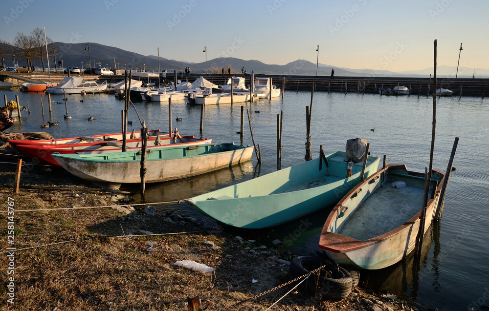 scenic view of Trasimeno Lake, with colorful boats moored in an harbor