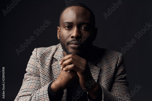 Dark key portrait of serious man with dark eyes, weared in plaid suit jacket. Studio shot
