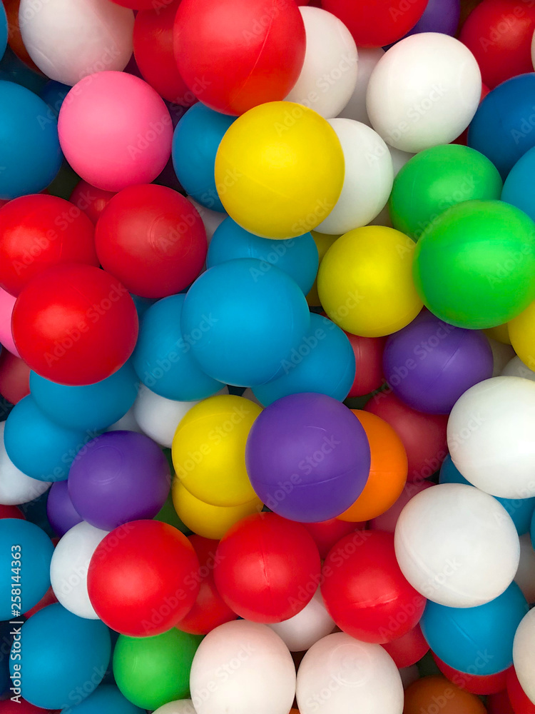 Top view colorful plastic balls in a pool. Plastic colorful balls for playing. Colorful plastic gum balls background in kid playroom or playground for children's holiday party concept Top view colorful plastic balls in a pool. Plastic colorful balls for playing. Colorful plastic gum balls background in kid playroom or playground for children's holiday party concept