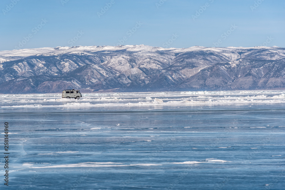 Obraz premium Baikal lake in winter day. Cracks on surface of the natural ice in frozen water behind the mountains at Baikal lake, Russia