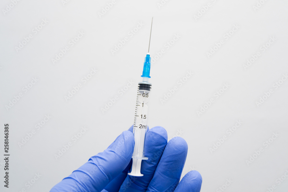 man holding a syringe in the hand with blue glove man holding a syringe in the hand with blue glove