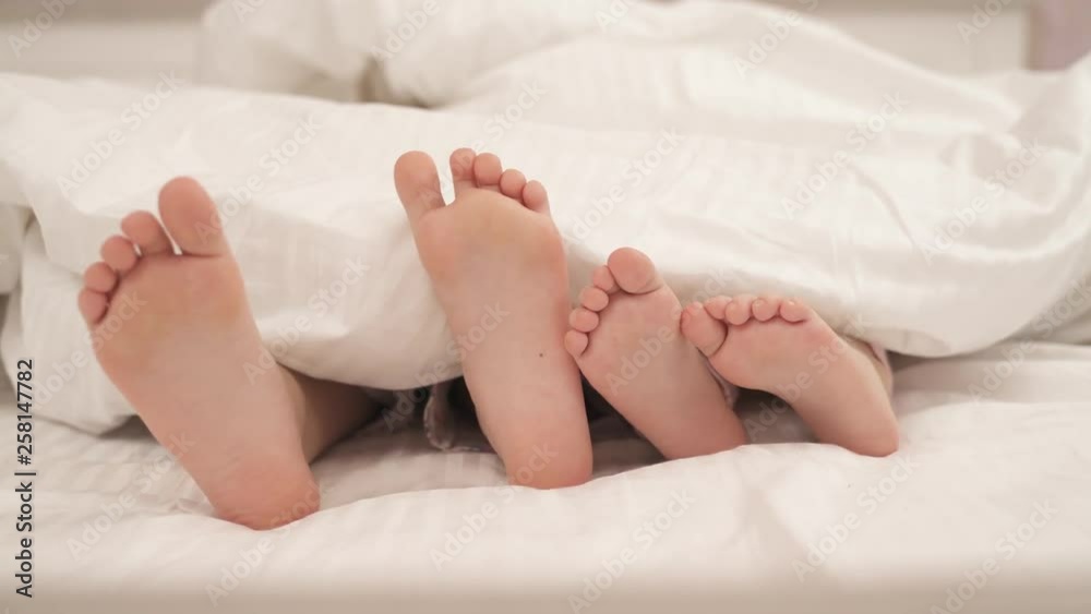Children's feet moving under blanket. Kids are lying in bed. Children's feet moving under blanket. Kids are lying in bed.