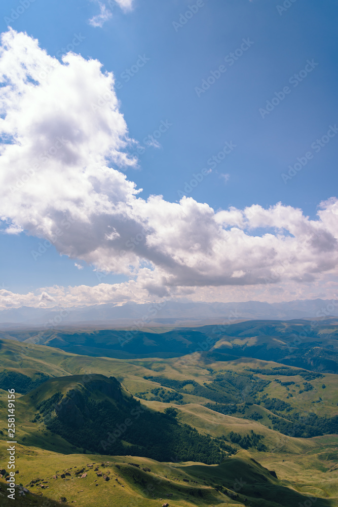 Fototapeta premium View from the Bermamyt Plateau on a summer day. Hills and clouds in the distance.