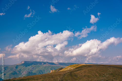 View from the Bermamyt Plateau on a summer day. Hills and clouds in the distance.