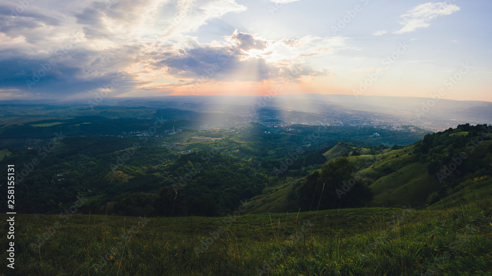 Sunset over Kislovodsk from a height in summer, the rays of the sun through the clouds.
