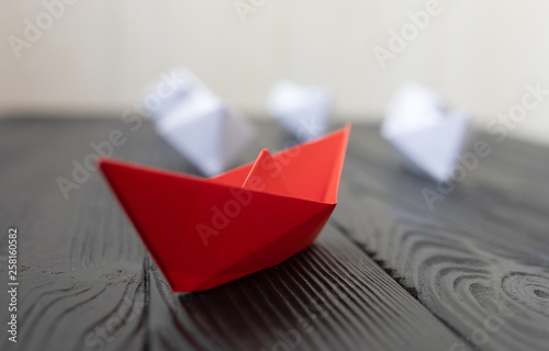 Leadership concept. Red leader paper ship leading among white on black background. 