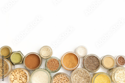 Top view of jars with grains, seeds, legumes, flours and various food ingredients. Healthy food concept.