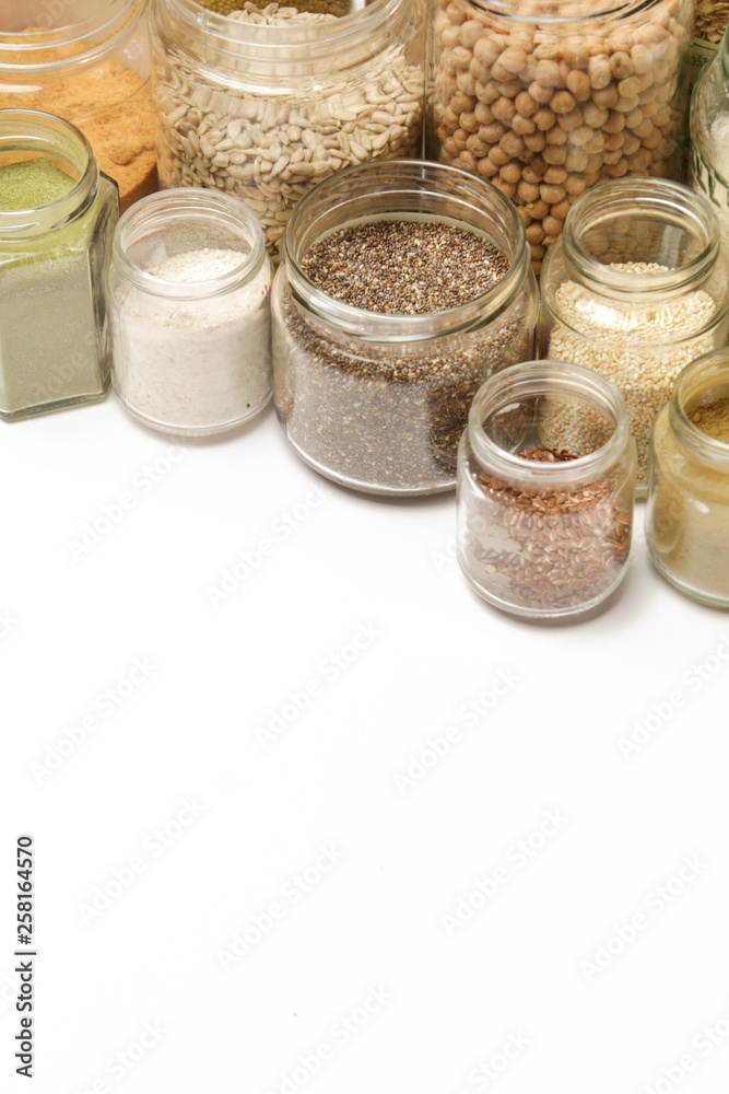 Top view of jars with grains, seeds, legumes, flours and various food ingredients. Healthy food concept.