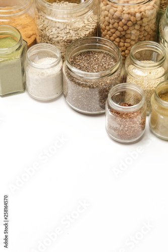 Top view of jars with grains, seeds, legumes, flours and various food ingredients. Healthy food concept. photo