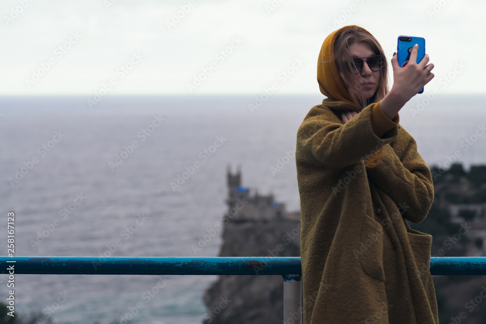 woman in an orange coat posing on the coast of the sea on the ruins of an old castle