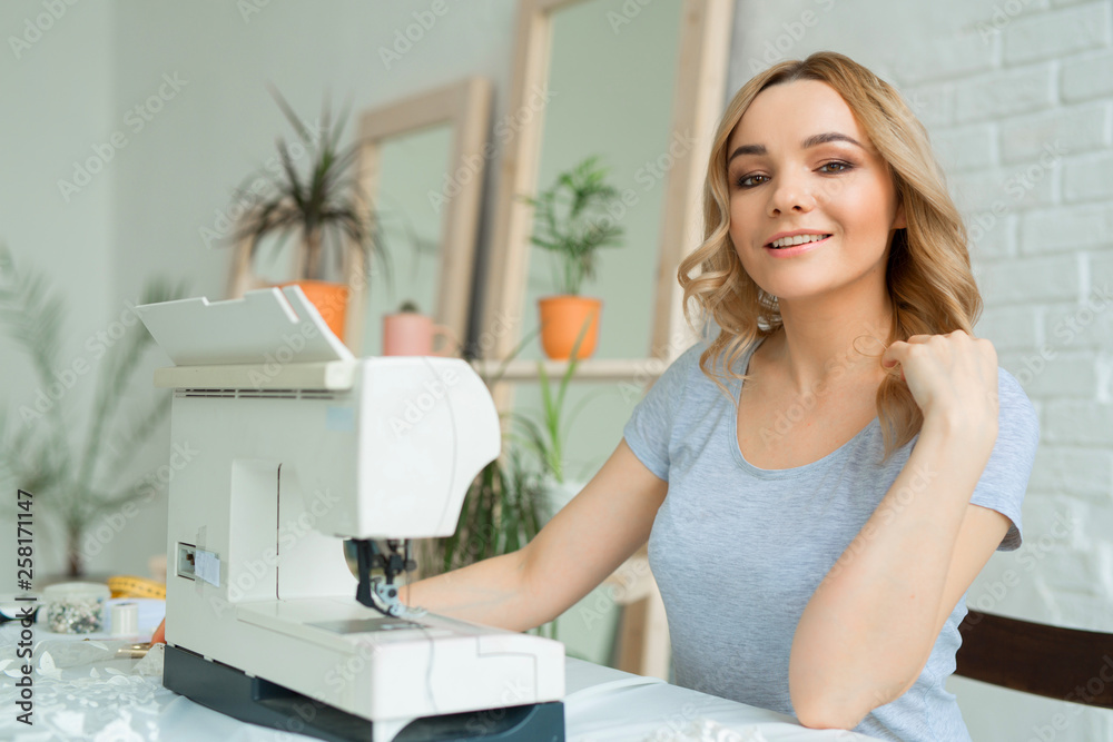 beautiful young girl in a factory with a sewing machine at the table beautiful young girl in a factory with a sewing machine at the table