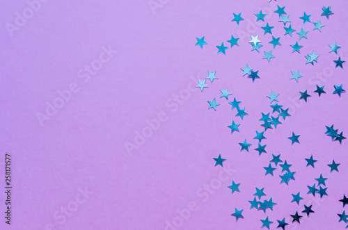 Holographic stars on trendy purple background. Festive backdrop. Top view. Copy space.