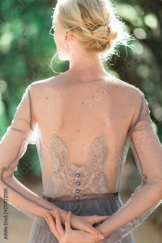 Stunning bride back portrait in beautiful wedding dress on natural background.
