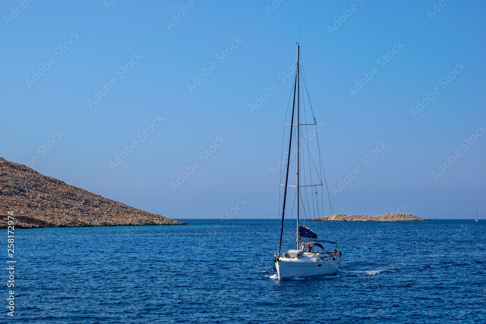 A sailing yacht crosses Emborio harbour on the Greek island of Halki (Chalki).