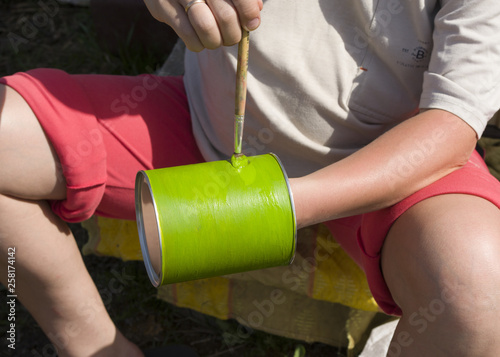 painting with a brush in green in the backyard