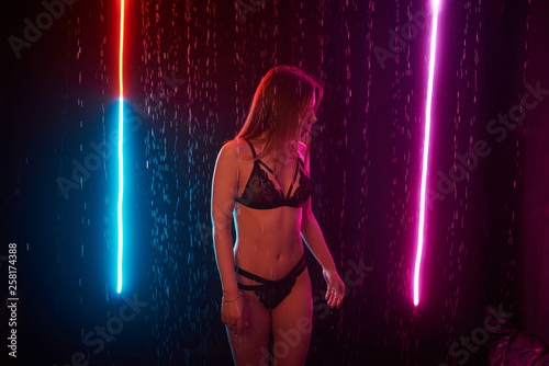 The girl in the rain in aquastudia. Neon light and sexuality.