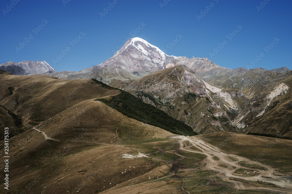 Caucasian mountains. A view of snow-covered summit of Mount Kazbek. Landscape with road.