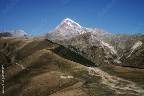 Caucasian mountains. A view of snow-covered summit of Mount Kazbek. Landscape with road.